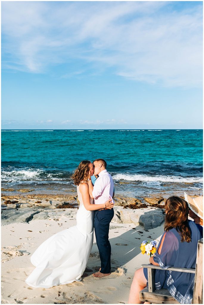 bride and grooms first kiss on the beach